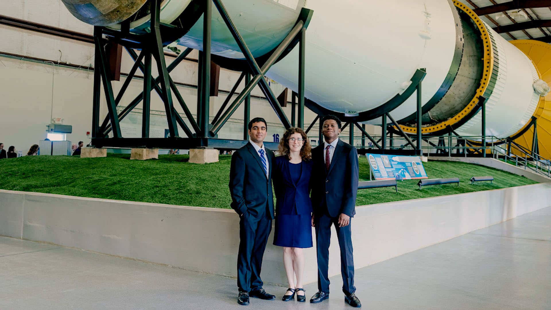 Students standing in front of a rocket booster