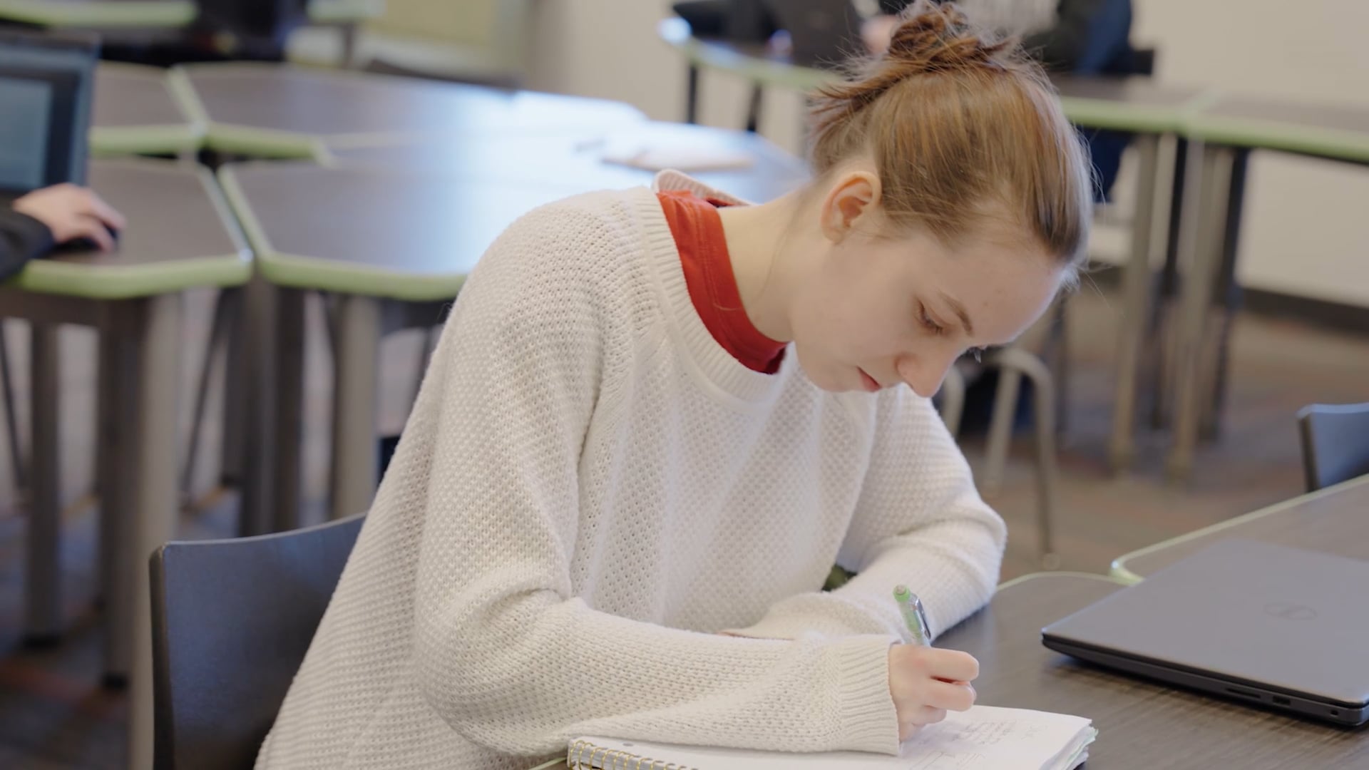 Female student writing on notebook in class
